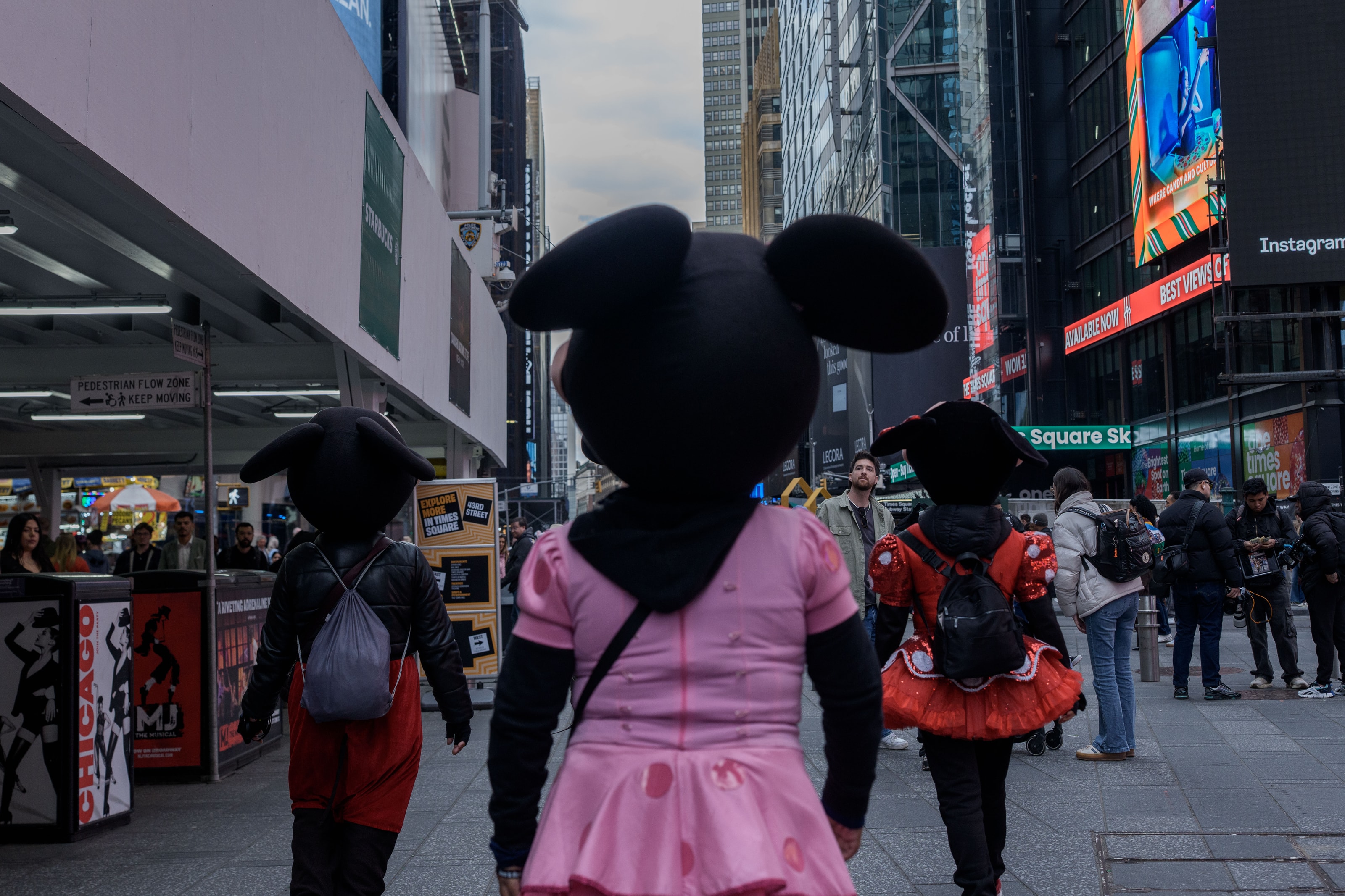 Costumed street performers in Times Square make their way home after work. They earn a living from tips for posing with tourists, typically receiving US$10–20 per photograph.